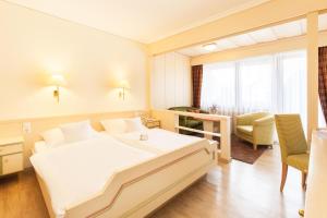 a hotel room with a large white bed and a desk at Landgasthof Hotel Hirsch in Loßburg