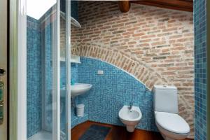 een badkamer met een toilet, een wastafel en een bakstenen muur bij Loft Mirano Tre (Alloggi alla Campana) in Mirano