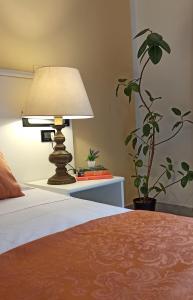 une lampe assise sur une table à côté d'un lit dans l'établissement Hotel Leonardo, à Pise