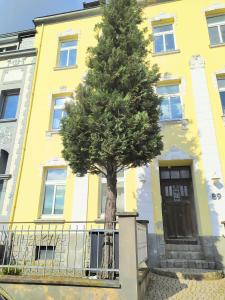 un árbol frente a un edificio amarillo en Super Apartments #1 mit Terrasse, #3 mit Aussicht und #7 mit Fernblick nahe Aachen, en Stolberg