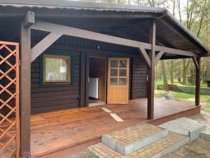 a small cabin with a wooden deck with a door at Ferienhaus Waldhütte Ferch in Schwielowsee +25 photos