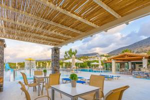 a patio with tables and chairs and a swimming pool at Villa Vicky in Hersonissos