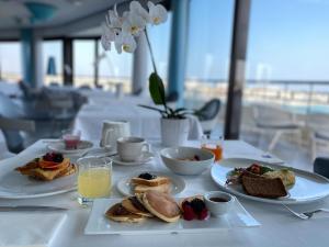 a table with plates of breakfast foods and a glass of orange juice at JR Hotels Bari Grande Albergo delle Nazioni in Bari