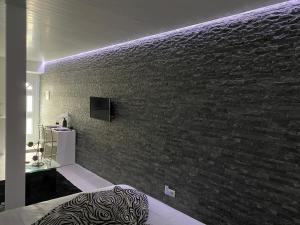 una camera da letto con un muro di mattoni e una TV di THE CEDAR TREE HOUSE Studio 48 a Sete Cidades