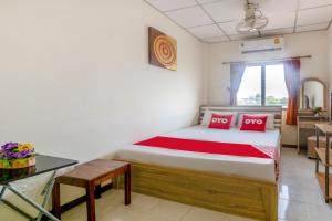 a bedroom with a bed with red pillows and a table at OYO 906 Bann One Love in Phra Nakhon Si Ayutthaya