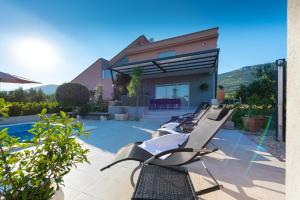 Villa Toni with 5 bedrooms and heated pool في قشتيلا: مجموعة من كراسي الصالة على فناء بجوار منزل
