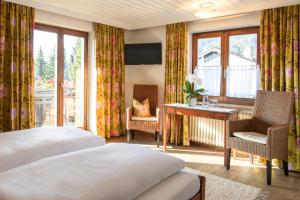 um quarto de hotel com uma cama, uma secretária e janelas em Gästehaus Schmid em Oberstaufen