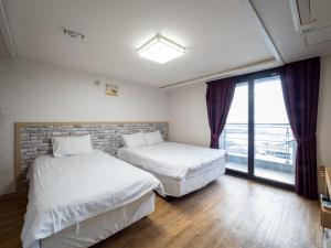 twee bedden in een kamer met een raam bij Jeju Moseulpo Hotel in Seogwipo