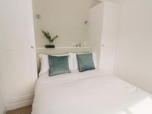 a white bed with two green pillows on it at Lake View in Bedford