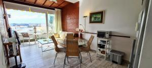 ein Wohnzimmer mit einem Tisch und Stühlen sowie einem Balkon in der Unterkunft VV Canteras Ático "by henrypole home" in Las Palmas de Gran Canaria