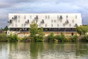 un bâtiment blanc à côté d'une étendue d'eau dans l'établissement Aiden by Best Western T'aim Hotel, à Compiègne