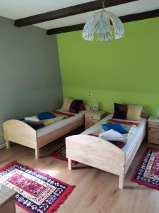Landgasthof Negrean في Modriach: سريرين في غرفة بجدران خضراء وأرضيات خشبية