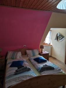 two beds in a room with a purple wall at Landgasthof Negrean in Modriach