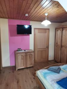 um quarto com uma parede rosa e uma televisão na parede em Landgasthof Negrean em Modriach