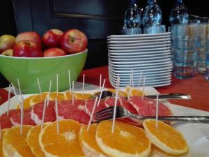 a plate of meat and oranges on a table with a bowl of apples at Ibis Katowice - Zabrze in Zabrze