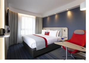 a hotel room with a bed and a red chair at Holiday Inn Express Edinburgh City Centre, an IHG Hotel in Edinburgh