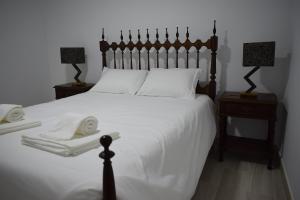 Casa da Avó Maria Ana في أرايولوس: غرفة نوم مع سرير مع شراشف بيضاء وجلستين نوم