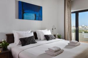 a bedroom with a large white bed with towels on it at Castello City Hotel in Heraklio