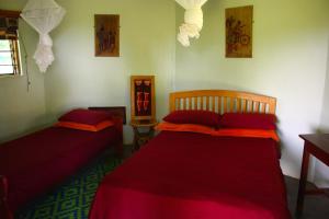 two beds in a room with red sheets at Red Chilli Rest Camp in Murchison Falls National Park