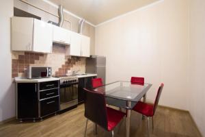 a kitchen with a glass table and red chairs at Apartment on Virmenska 3, with 2 separate bedrooms in Lviv