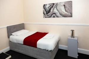 a small bedroom with a bed with a red blanket at AA Sunderland City South in Sunderland