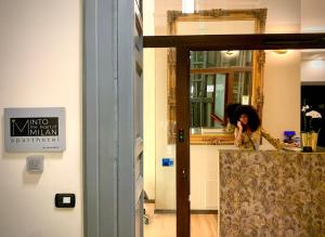 Eine Frau, die an einer Theke vor einem Spiegel sitzt. in der Unterkunft INTOMILAN Galleria Duomo I Boutique & Design Aparthotel in Mailand