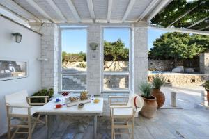 patio ze stołem i krzesłami oraz dużym oknem w obiekcie Villa Agia Thalassa Beachfront Luxury Villa Ampelas Paros w mieście Paros