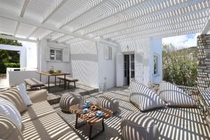 patio z krzesłami i stołem oraz białą pergolą w obiekcie Executive Paros Villa - 4 Bedrooms - Villa Island Spirit - Amazing Sea Views and Private Pool - Ampelas w mieście Paros