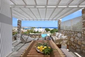 een patio met een bank en een tafel met fruit erop bij Executive Paros Villa - 4 Bedrooms - Villa Island Spirit - Amazing Sea Views and Private Pool - Ampelas in Kampos Paros