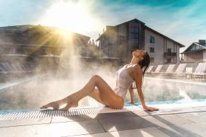 a woman sitting on the edge of a swimming pool at Karpatski Hotel & Spa in Bukovel