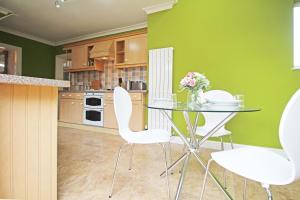 a kitchen with a glass table and white chairs at Queens Road - Luxury Spacious Home in Chester in Christleton