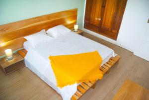 um quarto com uma cama branca com um cobertor amarelo em Sky Nautico Apartment em São Tomé