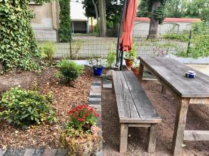 a wooden picnic table and some plants and an umbrella at Apartment Schloss Benrath in Greifswald