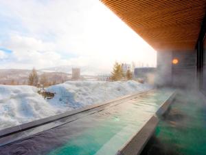 a hot tub covered in snow next to a building at Rusutsu Resort Hotel & Convention in Rusutsu +28 photos