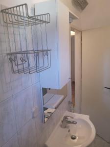 ein weißes Badezimmer mit einem Waschbecken und einem Spiegel in der Unterkunft Apartment Valentin in Ugljan