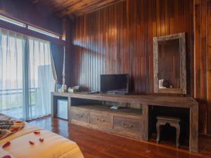 Habitación con escritorio de madera y TV. en Bali Jegeg Munduk Hotel, Bar, and Restaurant, en Munduk