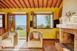 a living room with two chairs and a fireplace at Podere Lamino in Monticchiello