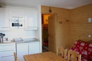 een keuken en eetkamer met een tafel en een koelkast bij travelski home select - Résidence Boedette in Les Menuires