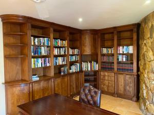 a library with wooden bookshelves and a wooden table at Amberley Mountain Reserve in Dullstroom