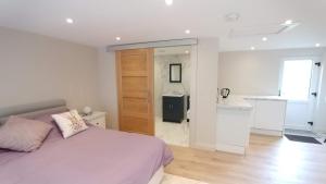 a white bedroom with a bed and a kitchen at The Garden Room, 1 Heath Cottage in Knutsford