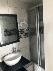uma casa de banho com um lavatório e um chuveiro em Kispet Deluxe Hotels&Suites em Oberhausen