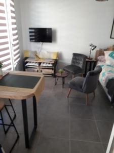 Beau studio refait a neuf centre ville avec clim balcon في ناربون: غرفة معيشة مع طاولة تنس وكراسي