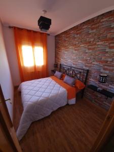 1 dormitorio con cama y pared de ladrillo en Chalet Las Praderas, en Chillarón de Cuenca