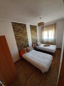 Habitación con 2 camas y pared de ladrillo en Chalet Las Praderas, en Chillarón de Cuenca