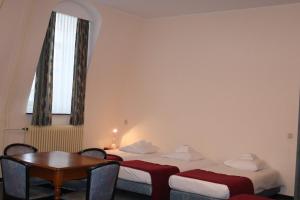 a room with two beds and a table and a window at Abdij Hotel Rolduc in Kerkrade