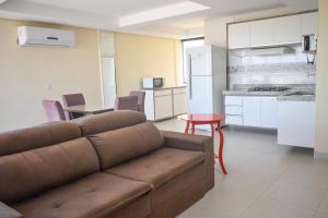 a living room with a couch and a kitchen at Hotel Vale da Serra in Parauapebas