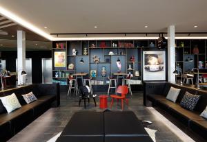 a living room with couches and a table and chairs at citizenM Copenhagen Radhuspladsen in Copenhagen