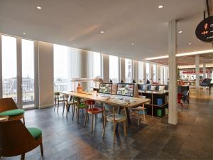a restaurant with a long table and chairs and windows at citizenM Copenhagen Radhuspladsen in Copenhagen