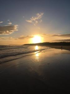 una persona caminando por la playa al atardecer en Causeway Street Holiday House Self Catering-Portrush, en Portrush