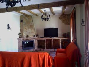 sala de estar con TV, mesa y chimenea en Casa Rural-Apartamento El Lebrillero, en Zahara de la Sierra